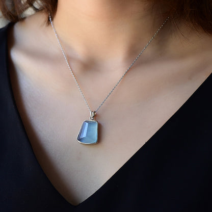 An aquamarine gemstone pendant with a chain around the neck