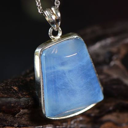 An aquamarine stone necklace visible from the left side